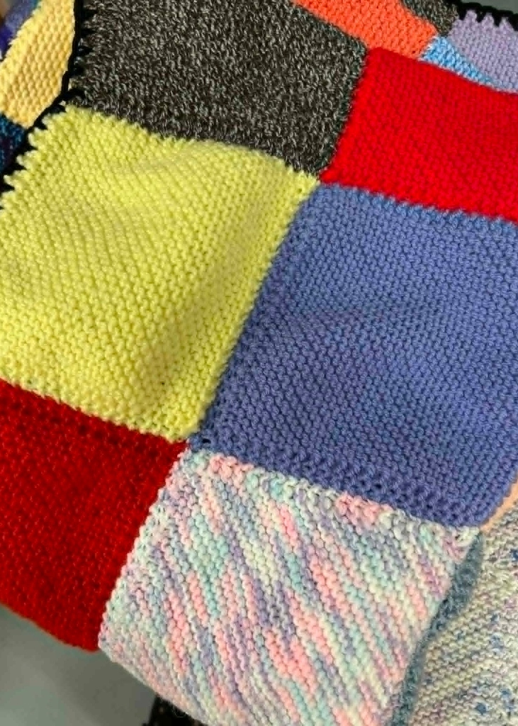 Colourful hand‑knitted garter stitch blanket made for the Blankets of Hope project, showing bright stripes and textured stitches.