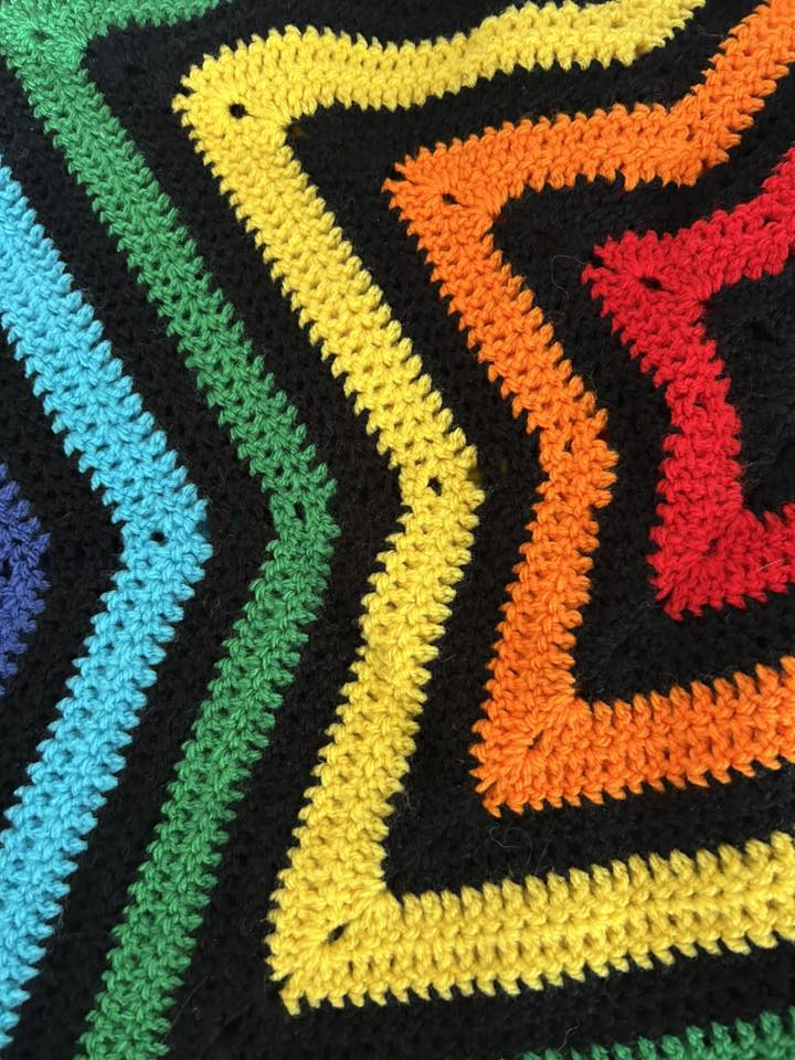 Vibrant crocheted star blanket made by Swindon Big Knit, featuring bold black contrast that makes the colourful star pattern stand out.