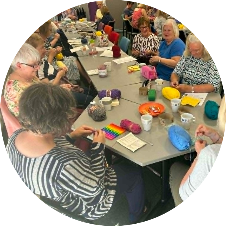 Swindon Big Knit members sitting together knitting, chatting and creating handmade items for the community.